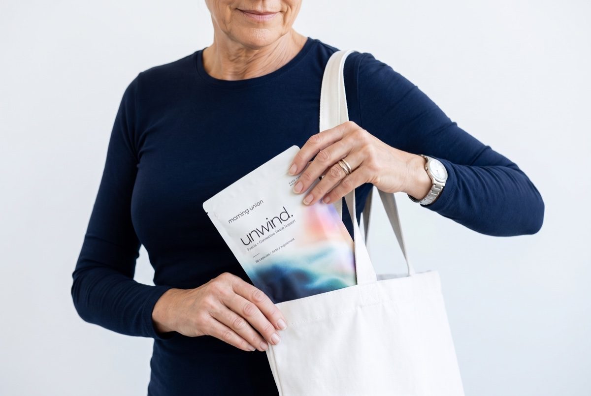 A woman slipping a pouch of unwind. into her tote bag